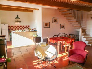 Un vaste espace de vie comprenant une table à manger, un fauteuil rouge et un escalier.