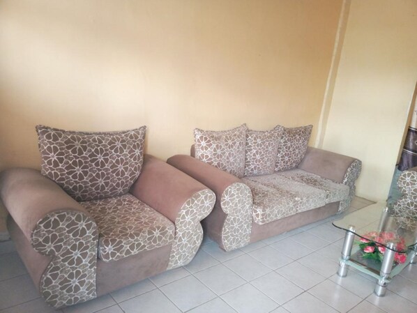 A living room with two sofas, a glass coffee table, and a decorative vase with flowers.