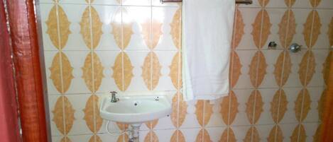A bathroom with patterned tiles, a white sink, and a towel rack.