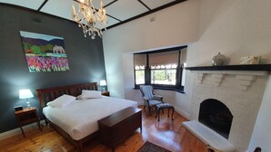 A bedroom with a bed, a chair, a fireplace, and a painting on the wall. - White Rocks (Tanunda)