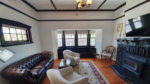 A living room with a leather sofa, patterned armchairs, a fireplace, and a television. - White Rocks (Tanunda)