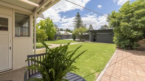 A covered patio area with a lawn, a brick pathway, and a view of neighboring buildings. - White Rocks (Tanunda)