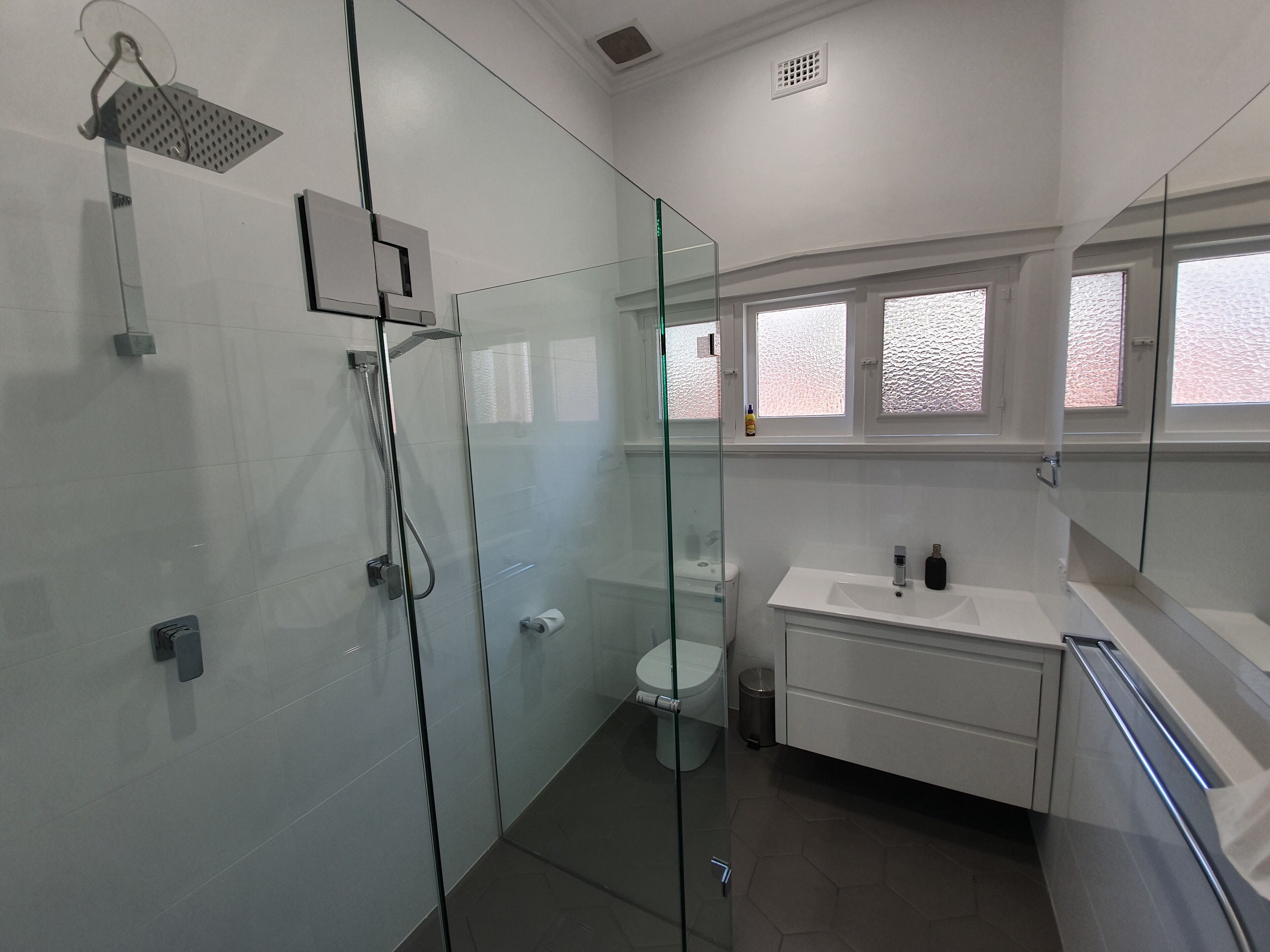 A modern bathroom with a glass-enclosed shower, a white sink, and a toilet.