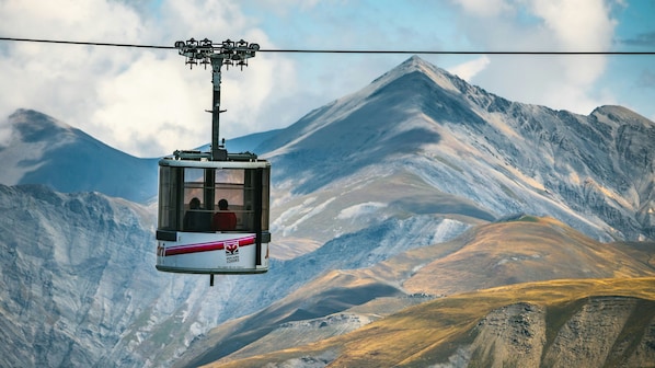 Un teleférico con pasajeros, suspendido sobre un paisaje montañoso.