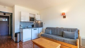 A compact living space with a kitchenette, a sofa, and a coffee table.