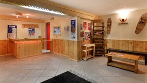 A reception area with a wooden reception desk, a bench, and a wall with posters and a heart-shaped decoration.