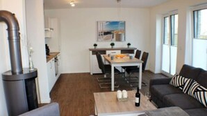 A modern living room with a grey sofa, a coffee table, and a dining area with a table and chairs. - Sielhuus 1 - Exclusive first floor apartment with sauna and box-spring beds (Fedderwardersiel-Butjadingen)