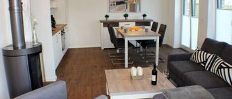 Een moderne woonkamer met een grijze bank, een salontafel en een eethoek met een tafel en stoelen.