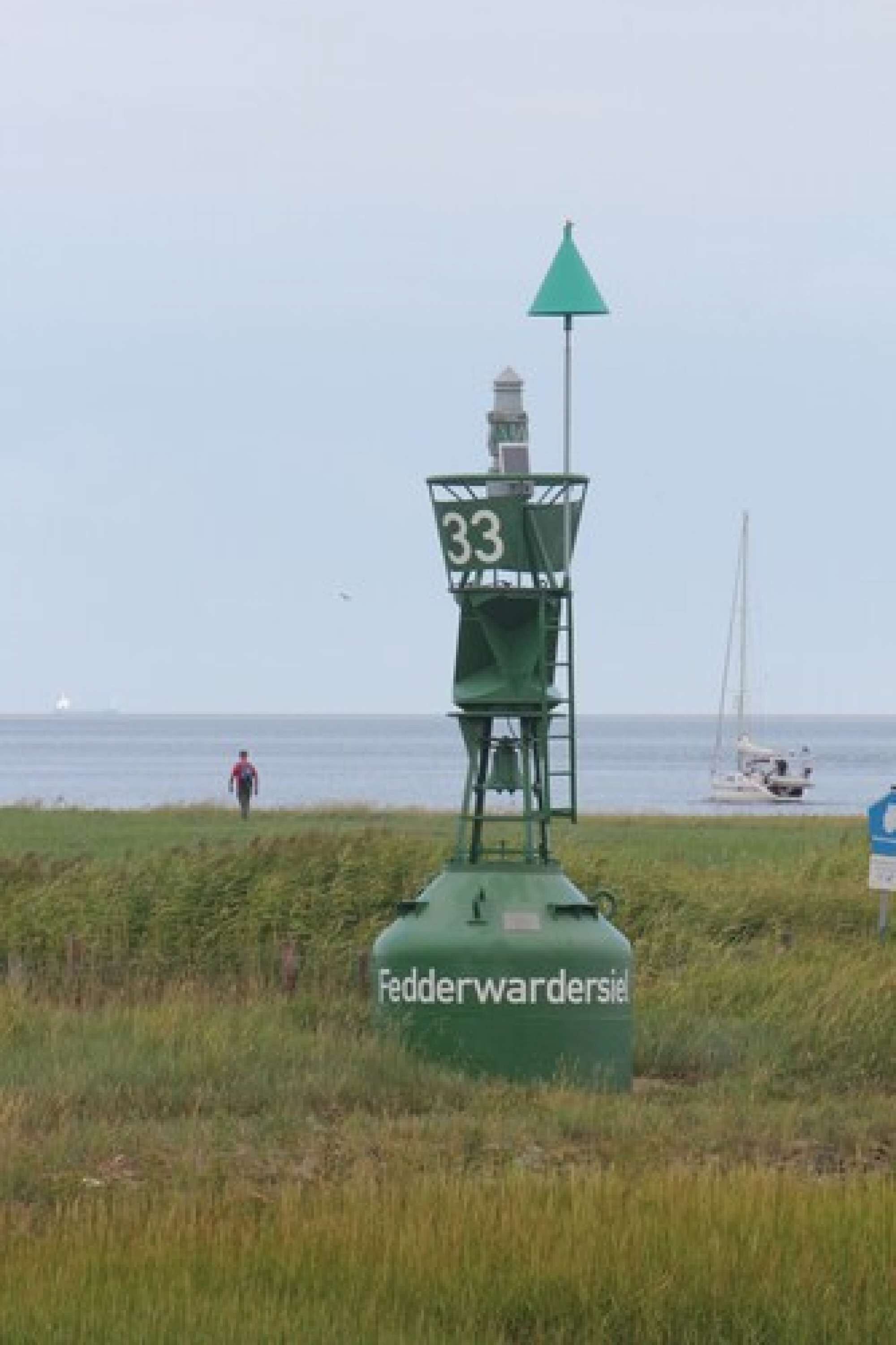 A lighthouse with the number 33, located near a body of water with boats.