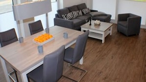 A modern living room with a sofa set, a coffee table, and a dining table with chairs. - Sielhuus 1 - Exclusive first floor apartment with sauna and box-spring beds (Fedderwardersiel-Butjadingen)