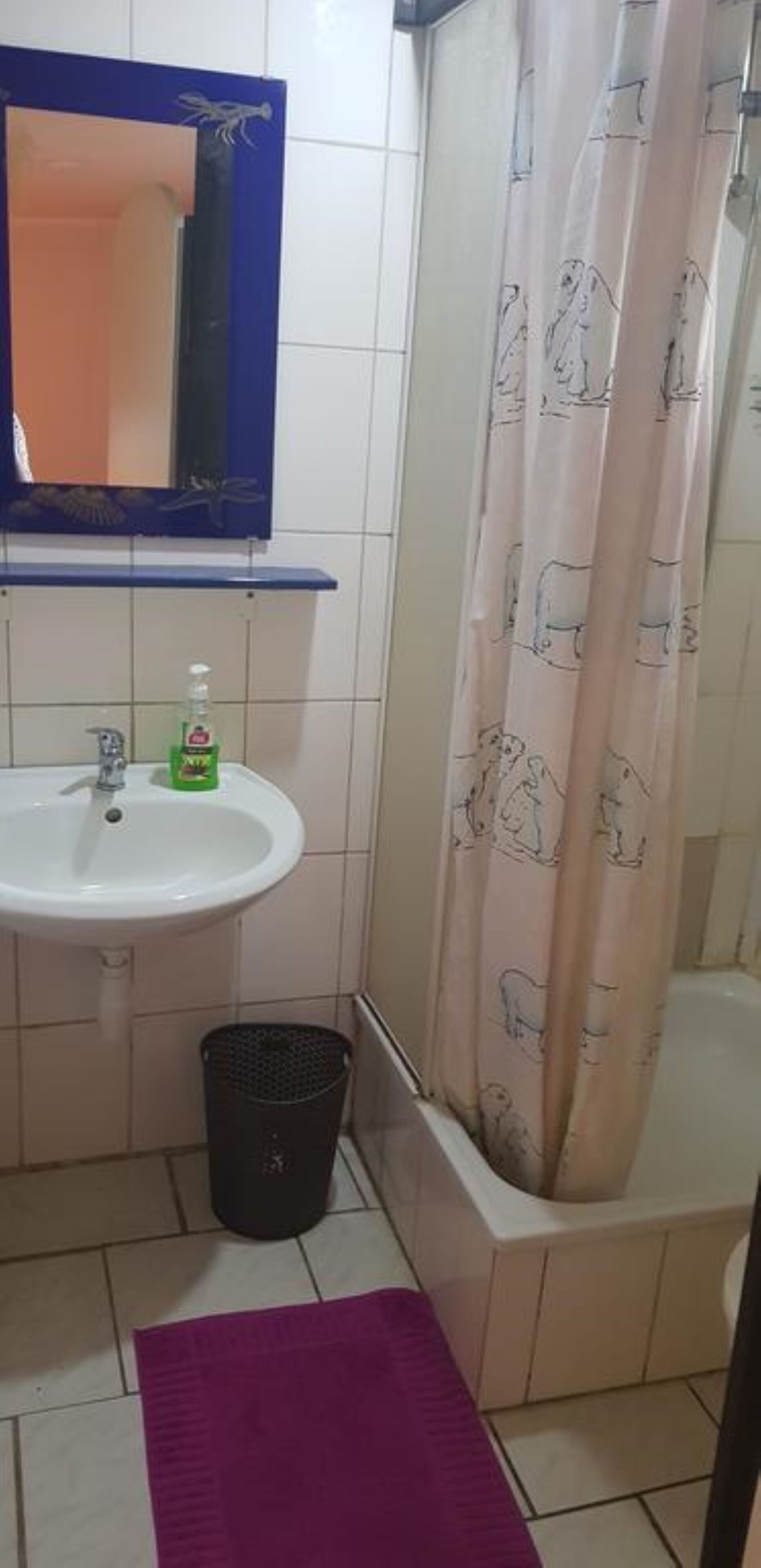 Une salle de bain avec un lavabo, un miroir et un rideau de douche.