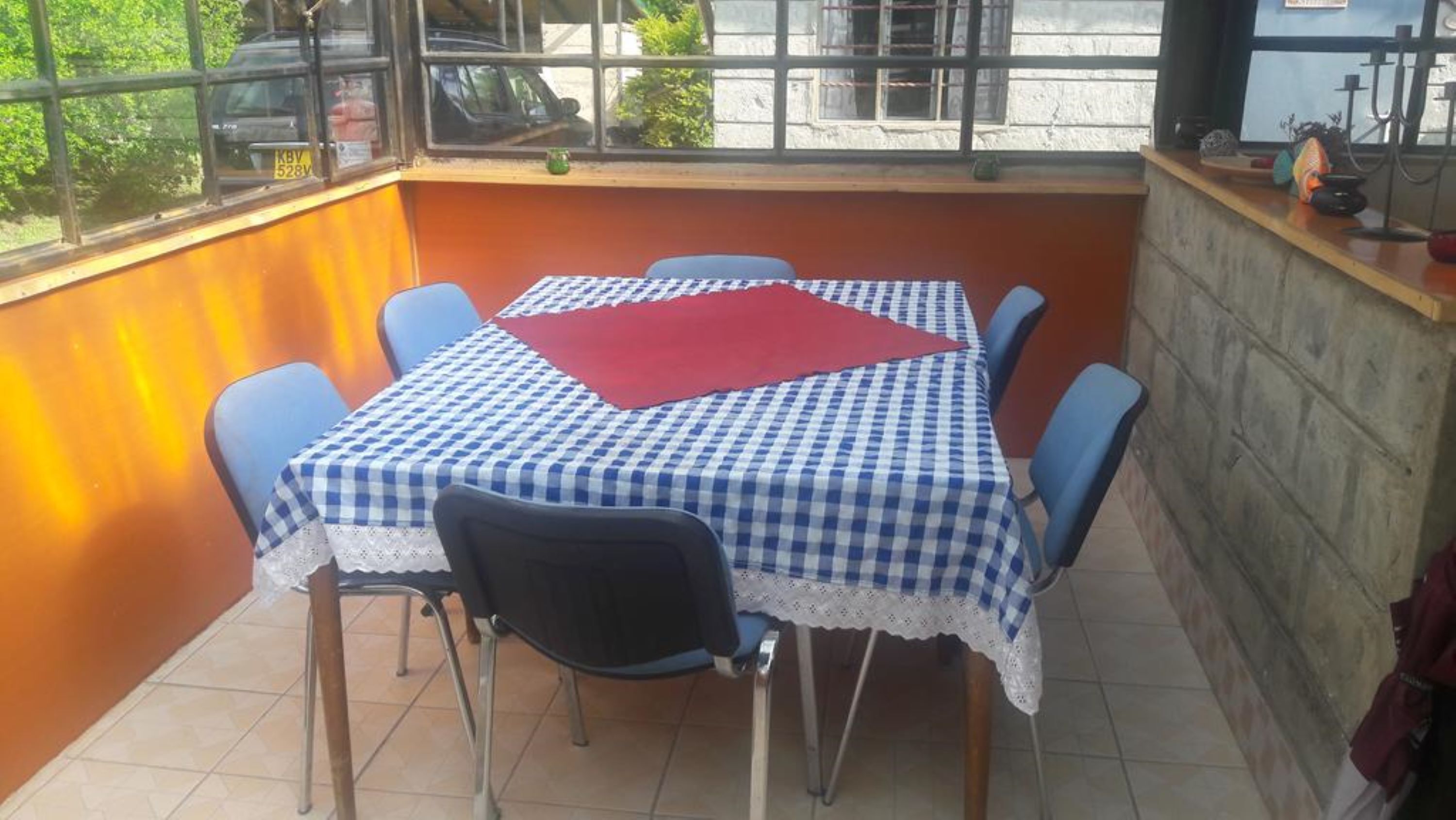 Un coin repas avec une nappe à carreaux, des chaises bleues et un set de table rouge.