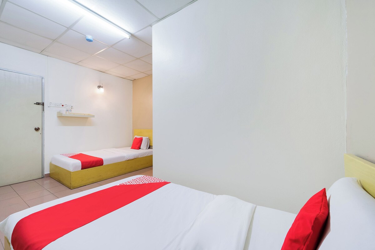 A hotel room with a bed, a bedside table, a nightstand, and a wall-mounted shelf.