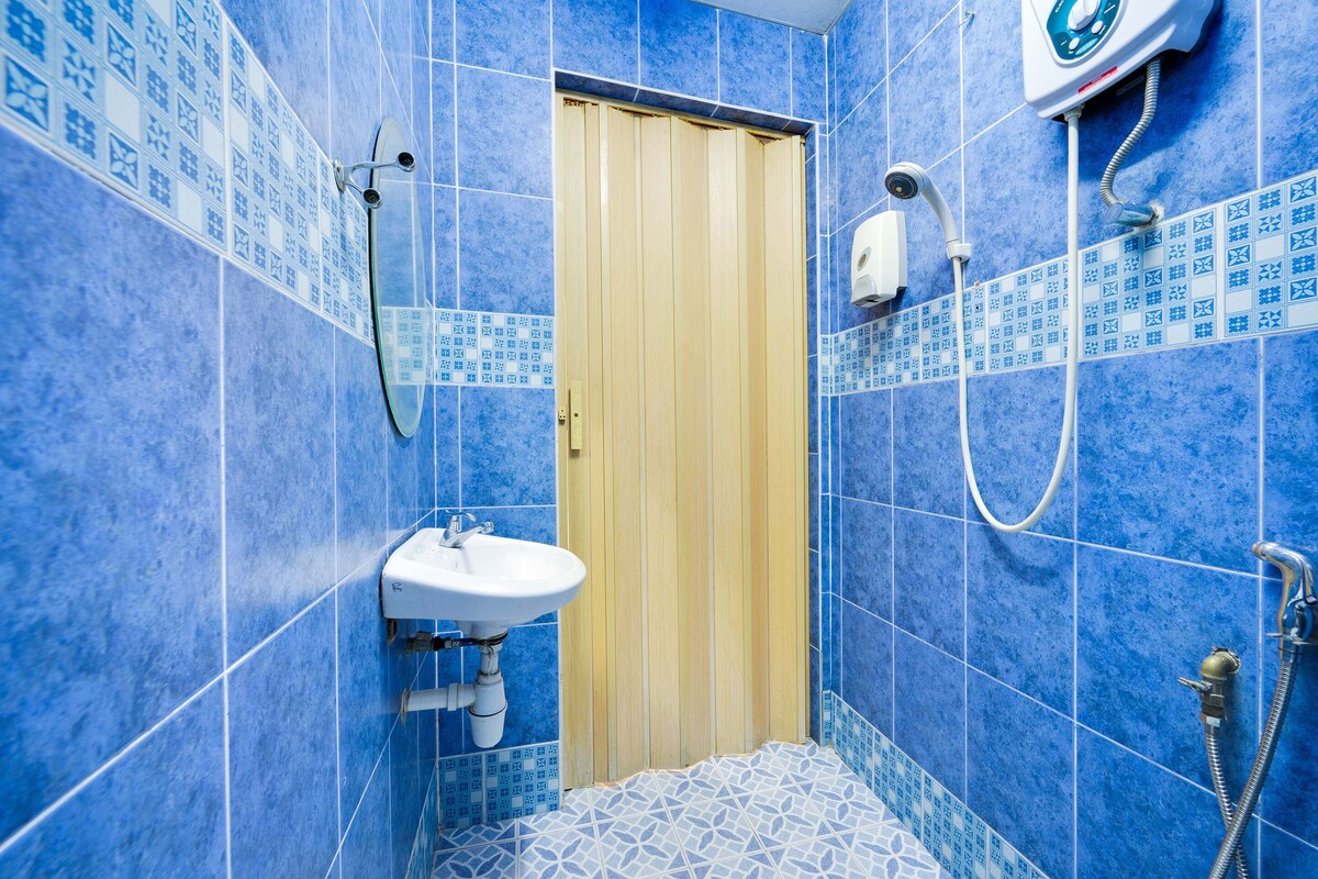 A bathroom with blue tiles, a wooden door, a sink, and a shower.