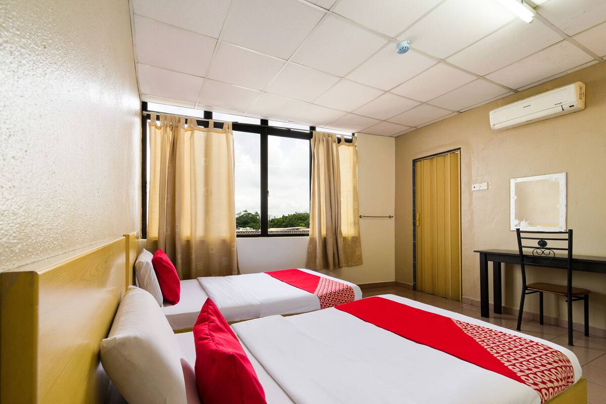 A hotel room with two beds, a desk, and a chair.