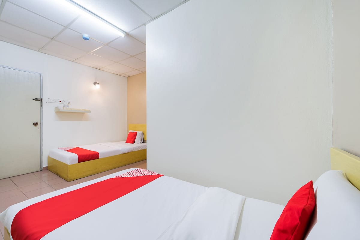 A hotel room with a bed, a bedside table, a wall-mounted shelf, and a door.