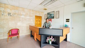 A hotel reception area with a wooden reception desk, a pink chair, and a framed picture on the wall. - OYO 89461 CP Hotel (Butterworth)