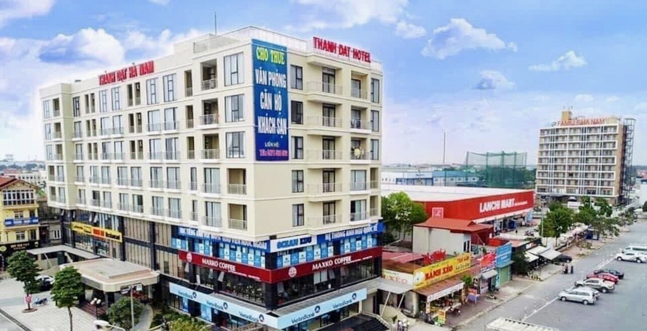Un hôtel à plusieurs étages, reconnaissable à son enseigne bien visible indiquant « HÔTEL THAMNIDAT » et « VAN PHONG CANH HO KHACH SA ».