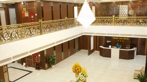 Eine Hotlellobby mit einer Rezeption, einer Chandelüster und einer dekorativen Pflanzengestaltung.