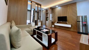 Ein modernes Wohnzimmer mit einer Couch, einem Couchtisch, einem Fernseher und einem Kühlschrank.