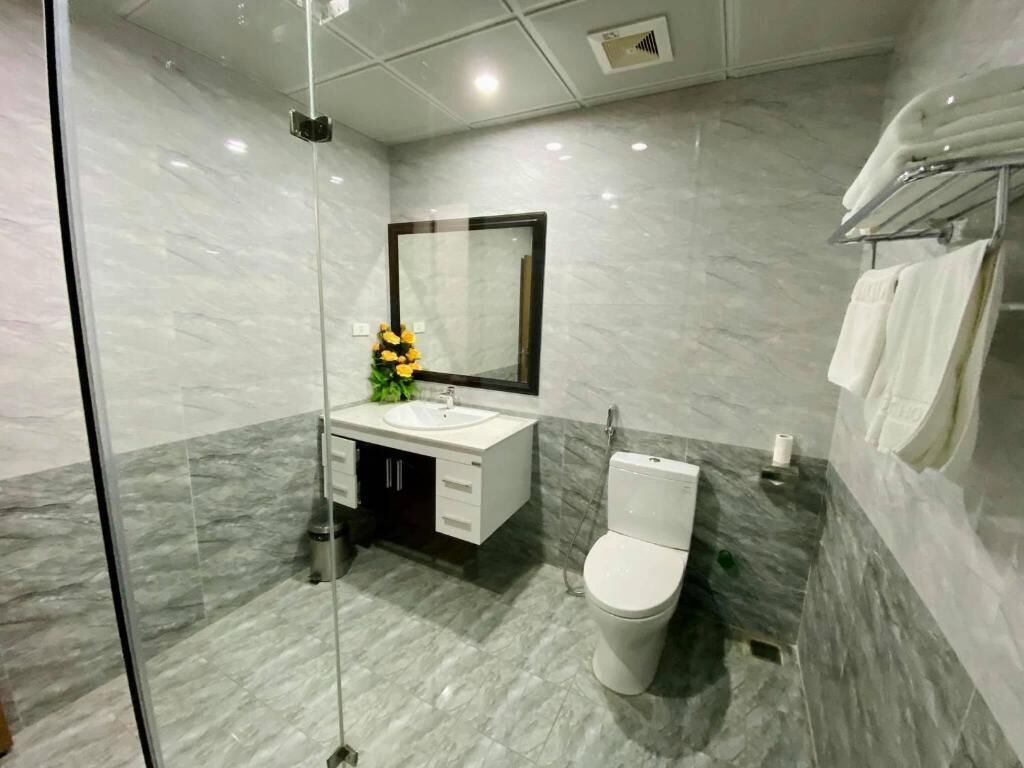 A modern bathroom with a glass shower enclosure, a white toilet, and a marble-tiled floor.