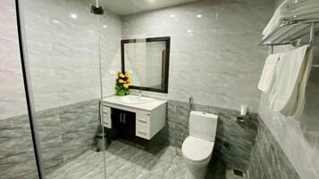 A modern bathroom with a glass shower enclosure, a white toilet, and a marble-tiled floor.