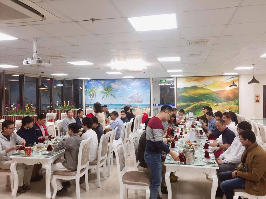 Un restaurante con varias mesas y sillas, un proyector instalado en el techo y murales decorativos en las paredes.