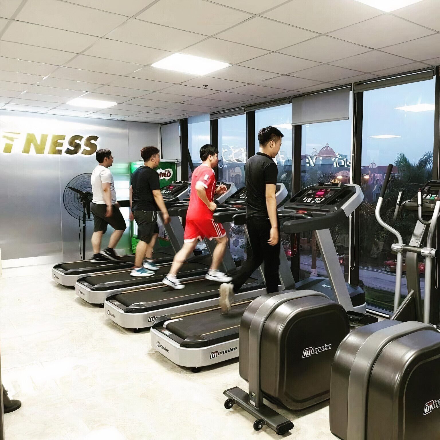 A gym with treadmills and a wall with the word "NESS".