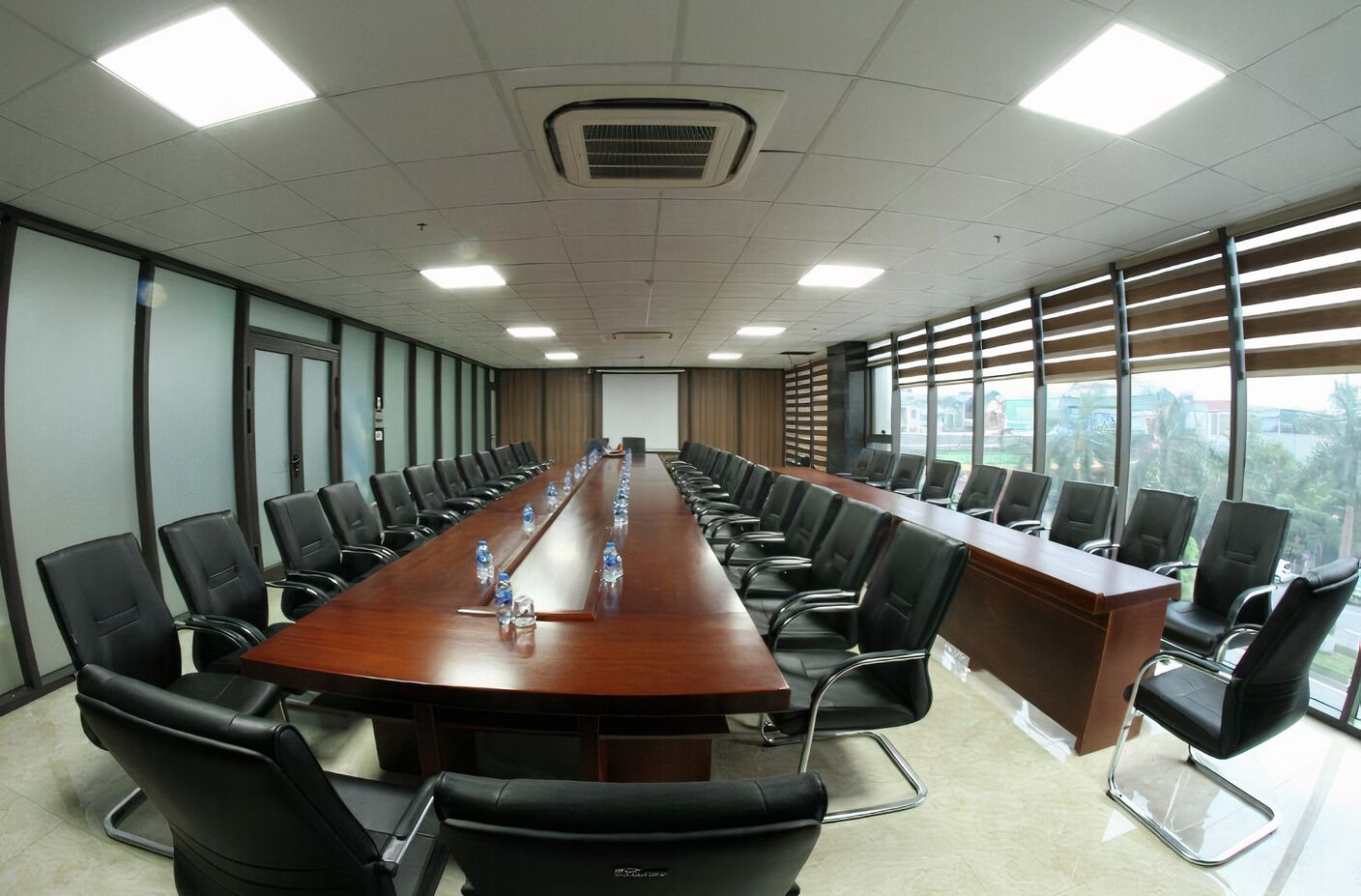 Un salón de conferencias con una mesa larga, sillas negras y un ventanal con vistas.