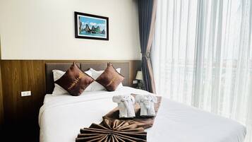 Ein Hotelzimmer mit einem ordentlich bezogenen Bett, einem gerahmten Bild an der Wand und einem Fenster mit Vorhängen.