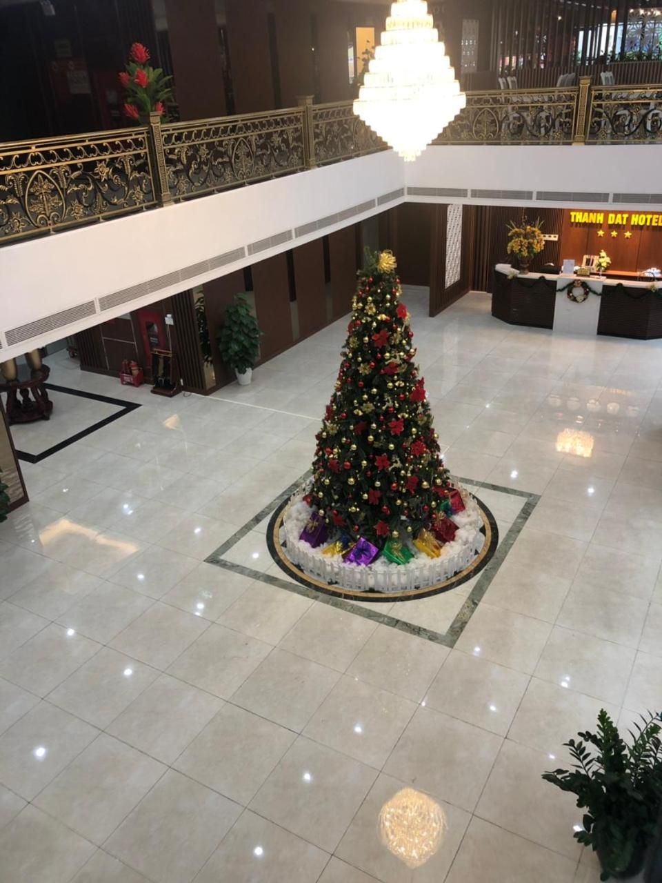 A hotel lobby with a large Christmas tree, a reception desk, and a chandelier.