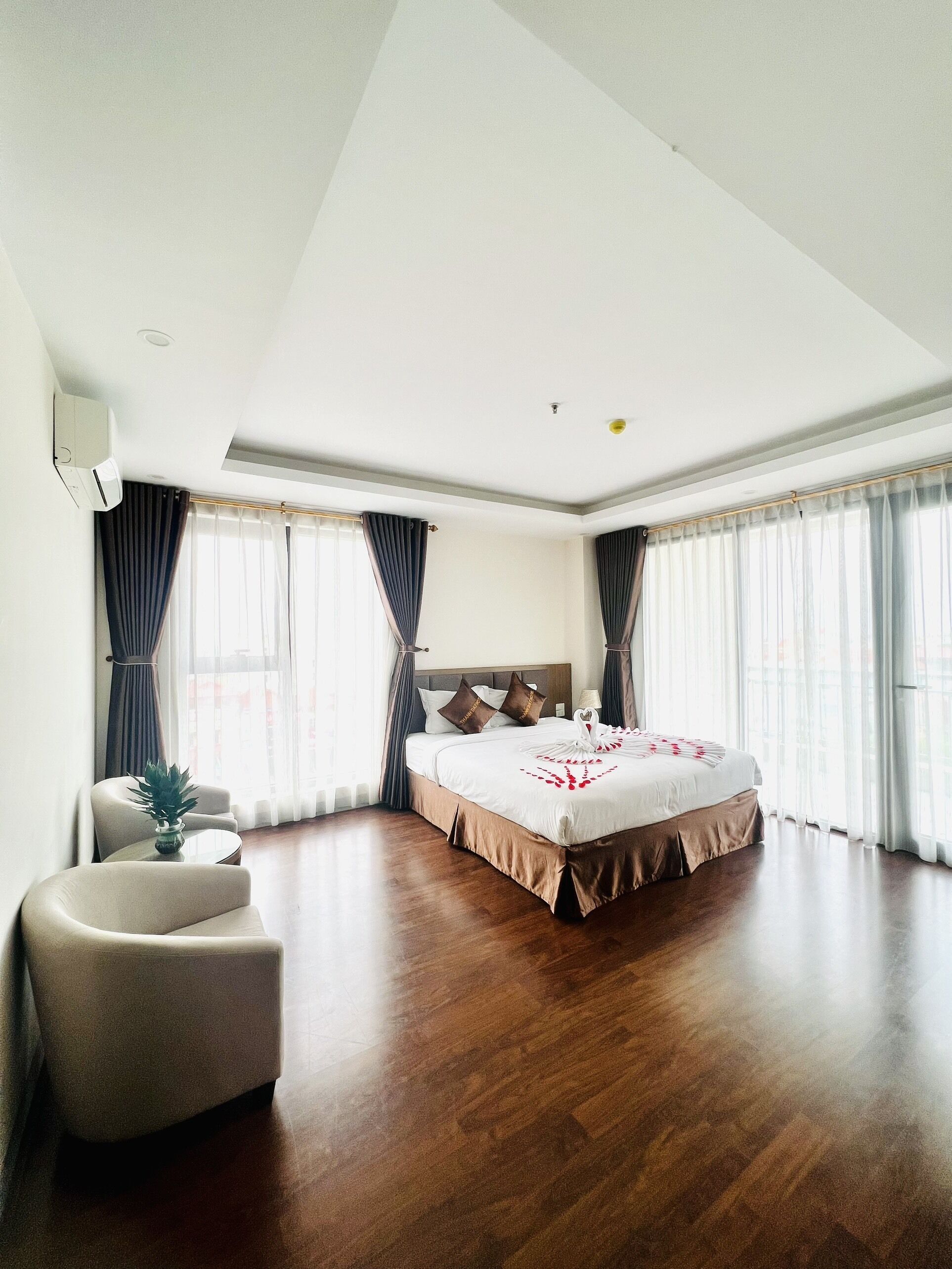 A modern hotel room with a large bed, a seating area, and a view of the city.