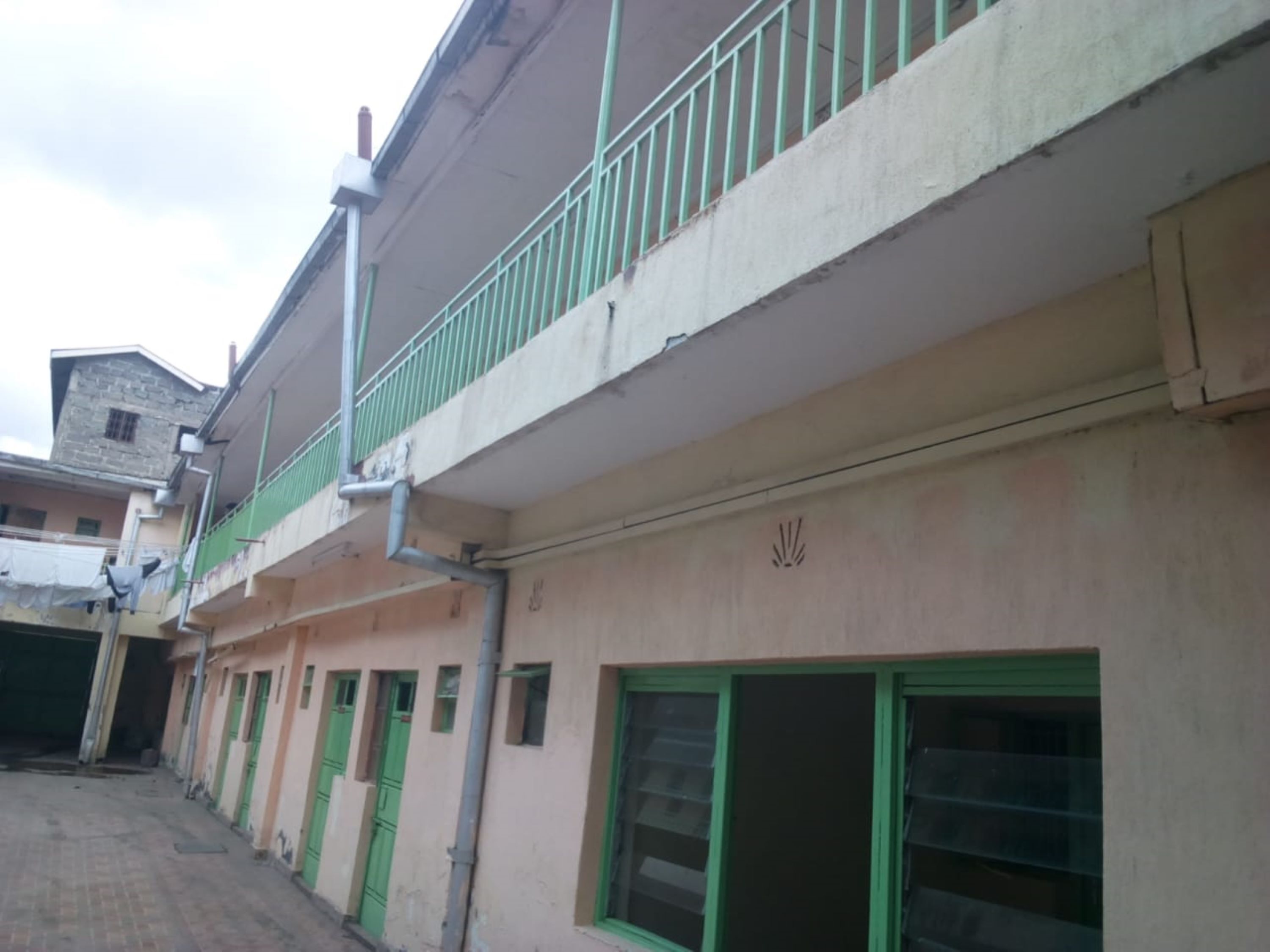 A building with a green balcony, multiple doors, and windows.
