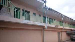 Ein Gebäude mit einer rosafarbenen Fassade, grünen Geländern und einer sichtbaren Garagentür.
