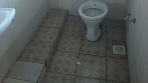 Ein kleines Badezimmer mit Fliesen, einer Toilette, einem Waschbecken und einem Fenster.