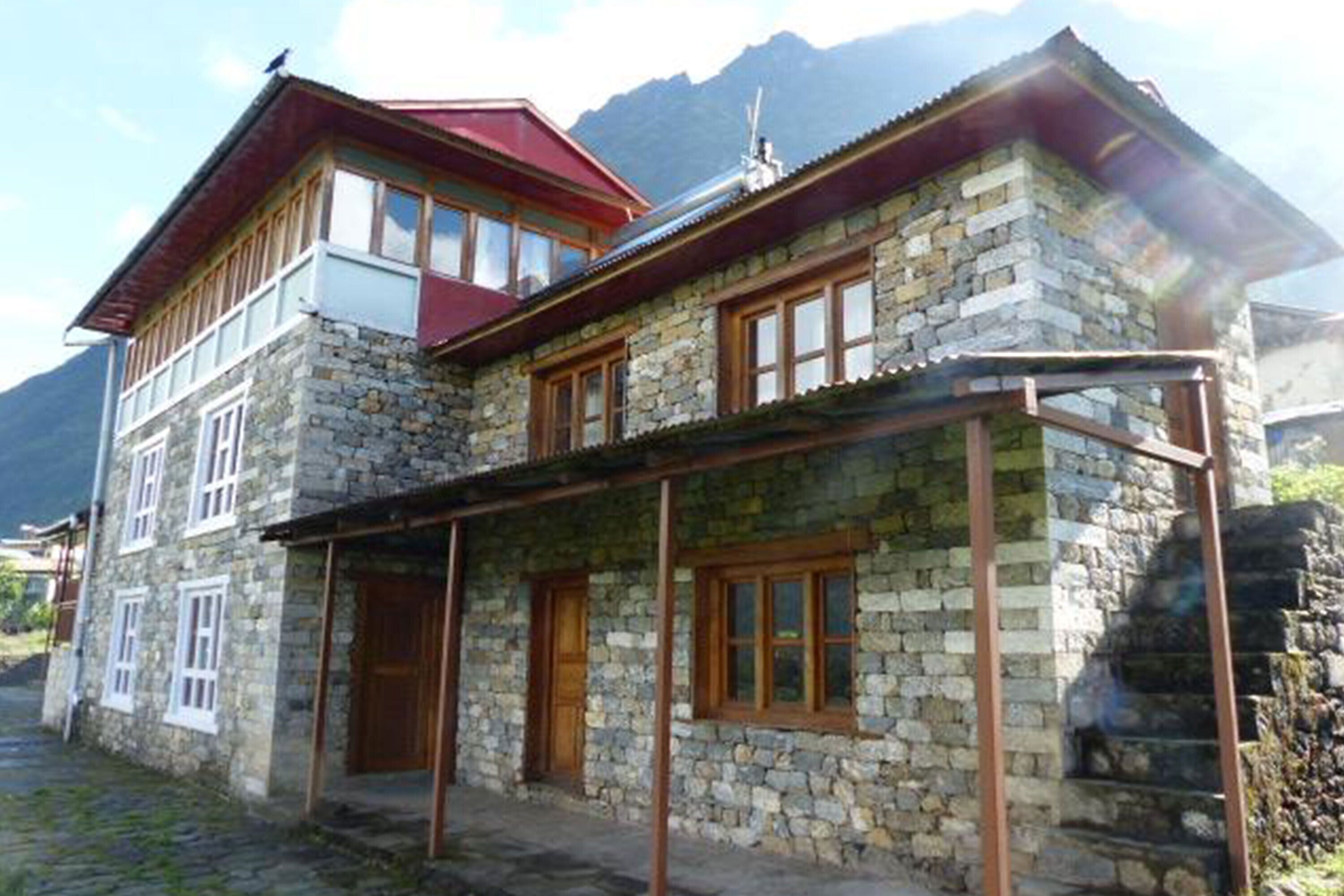 Un edificio de piedra con tejado rojo y puertas de madera, que cuenta con un balcón y un porche cubierto.