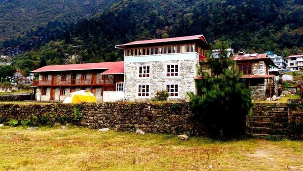 A stone building with a red roof, a balcony, and a stone wall in a mountainous area. - Lukla Airport Resort, Lukla  (Lukla)