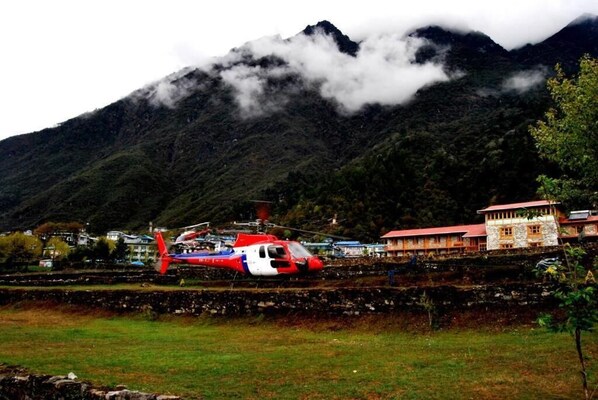 A helicopter on a helipad with a mountainous backdrop.