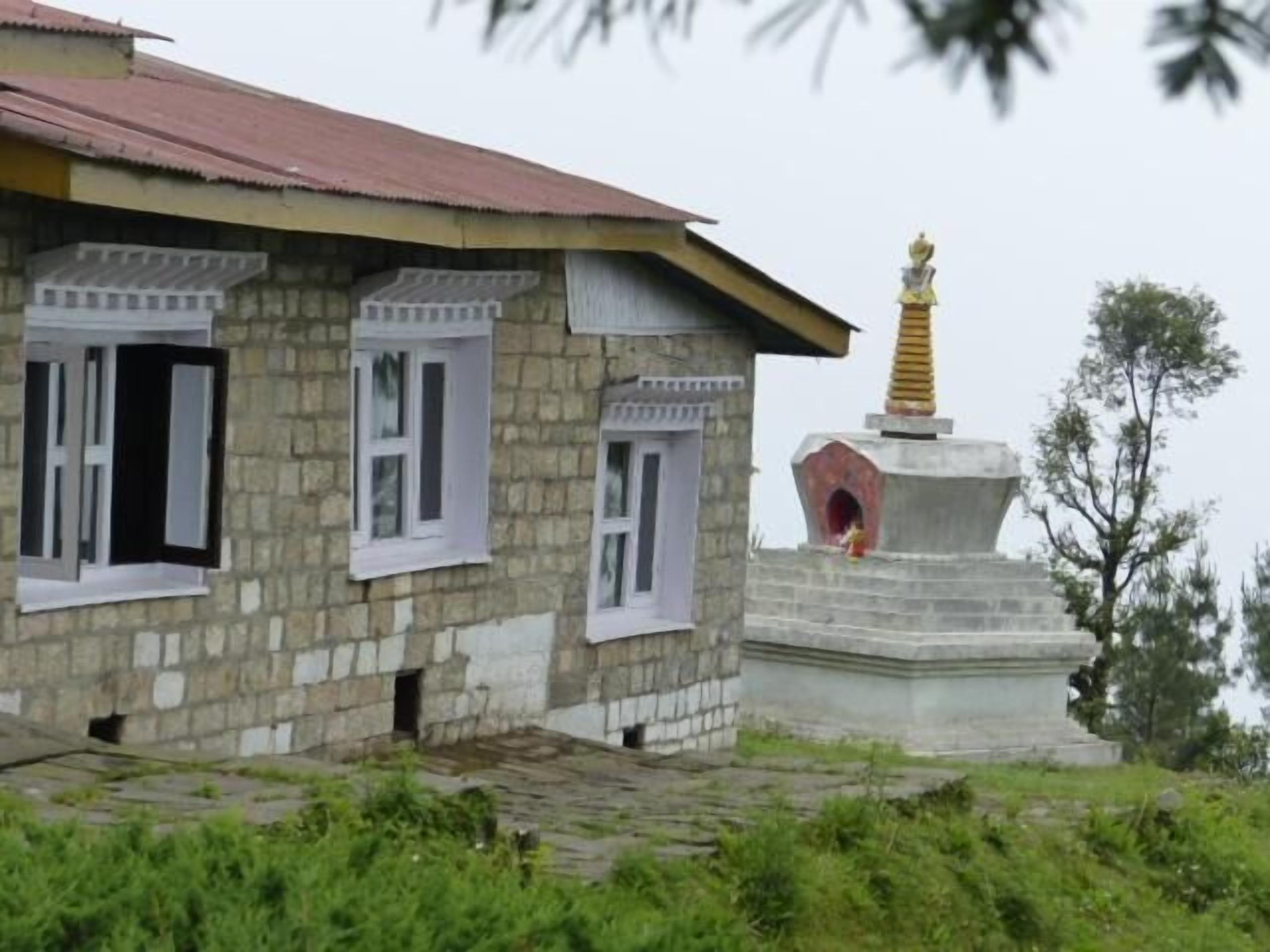 A stone building with a red roof and white window frames.