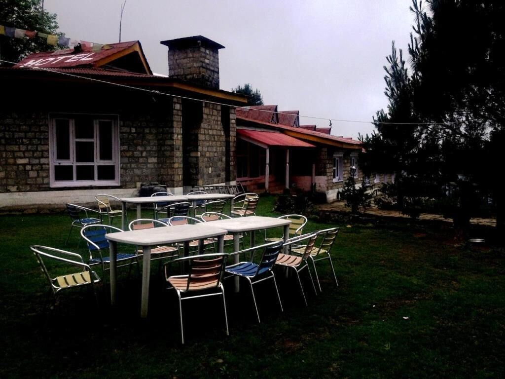 A hotel with outdoor seating and a stone facade.