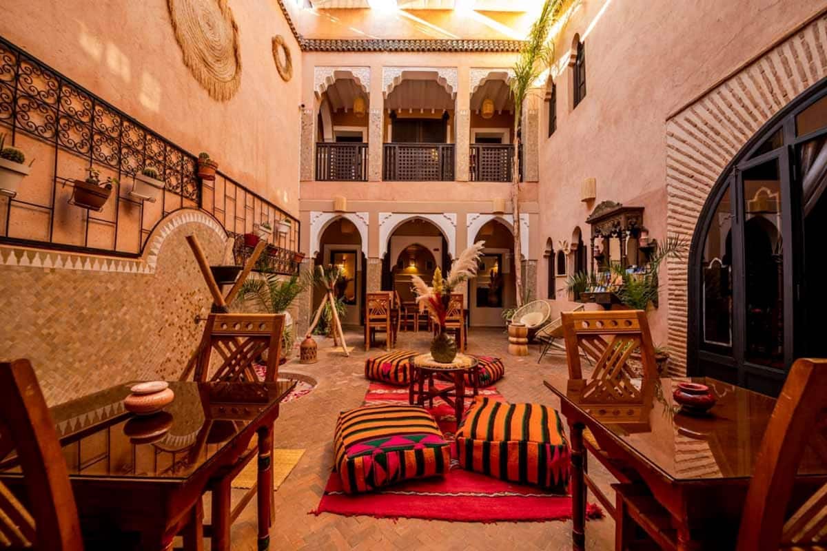A traditional Moroccan interior with a courtyard, wooden furniture, and arches.