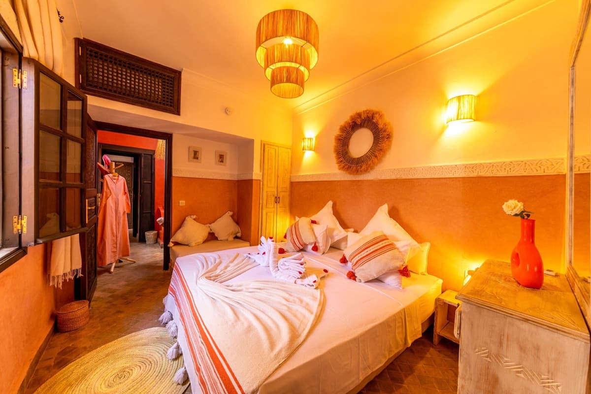 A hotel room with a large bed, a nightstand, a dresser, a mirror, and a wall-mounted light fixture.