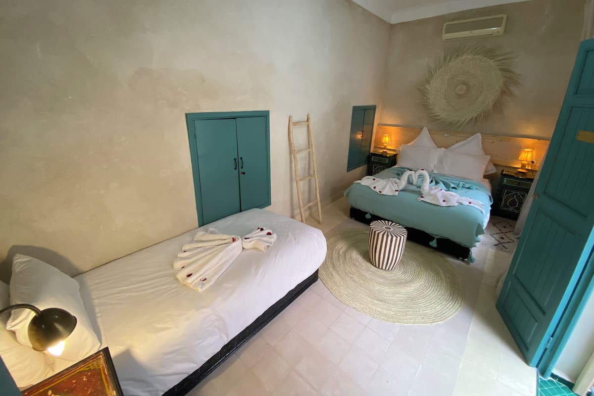 A bedroom with a bed, a wardrobe, a bedside table with a lamp, and a decorative sun-shaped wall hanging.