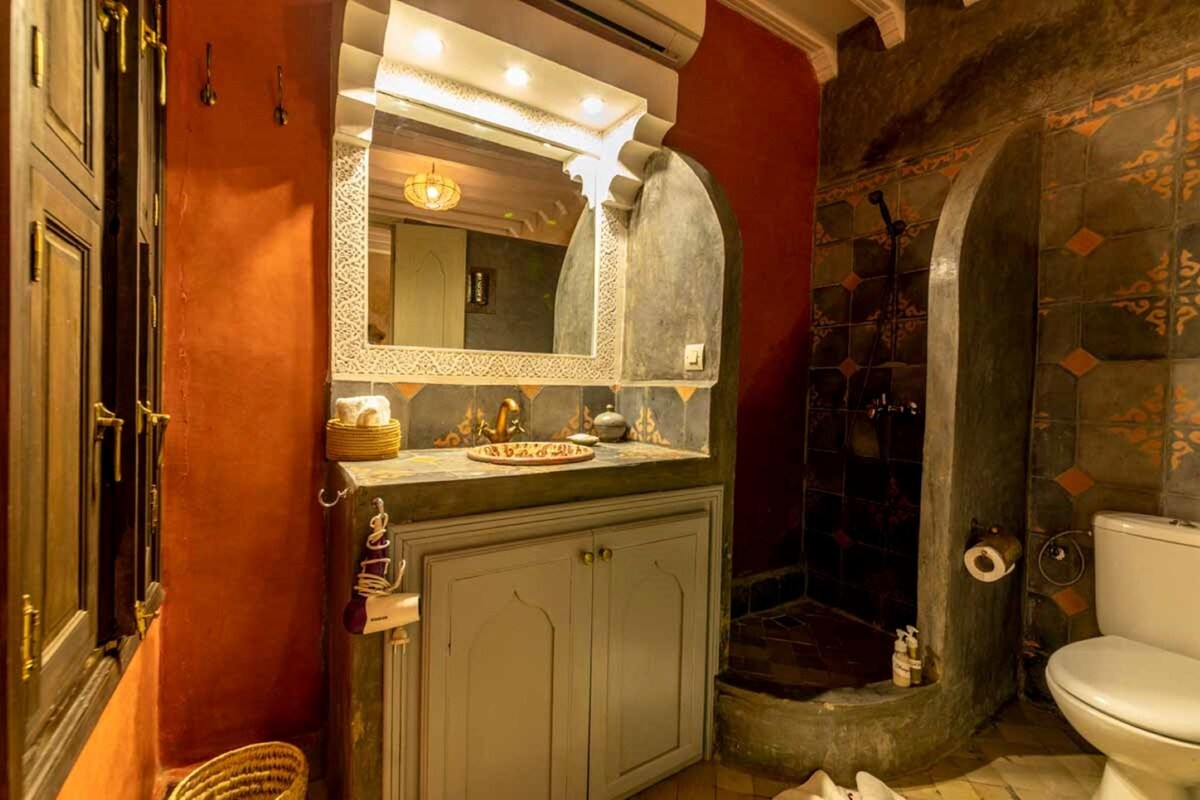 A bathroom with a vanity, mirror, and shower area.