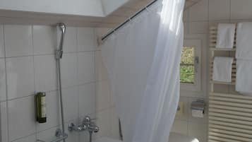 A modern bathroom with a skylight, a bathtub, a shower, and a toilet.
