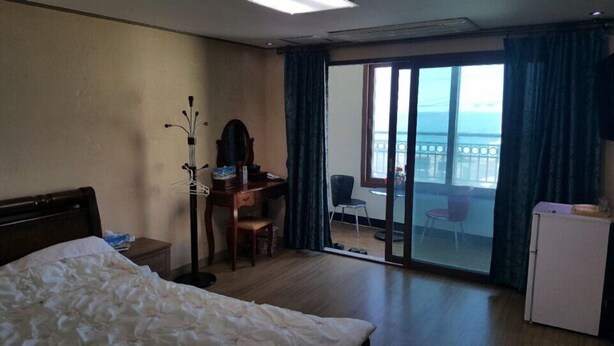 Ein Hotelzimmer mit Bett, Schreibtisch, Stuhl und Meerblick durch eine Schiebetür.