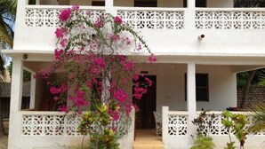 A two-story building with a balcony, white lattice railings, and pink bougainvillea flowers. - Dudu Villas n Cottages (Lamu)