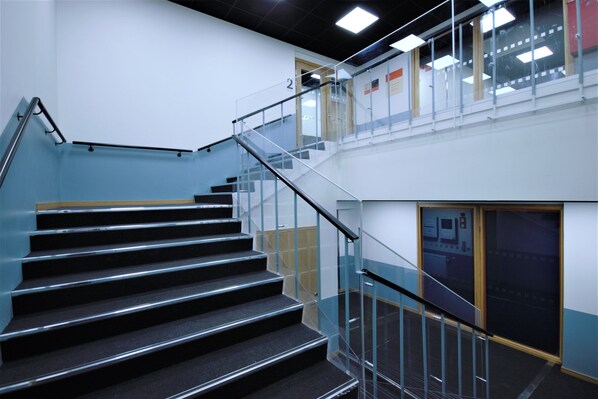 A staircase with glass railings and a handrail, leading to an upper floor. - Forenom Aparthotel Varkaus (Varkaus)