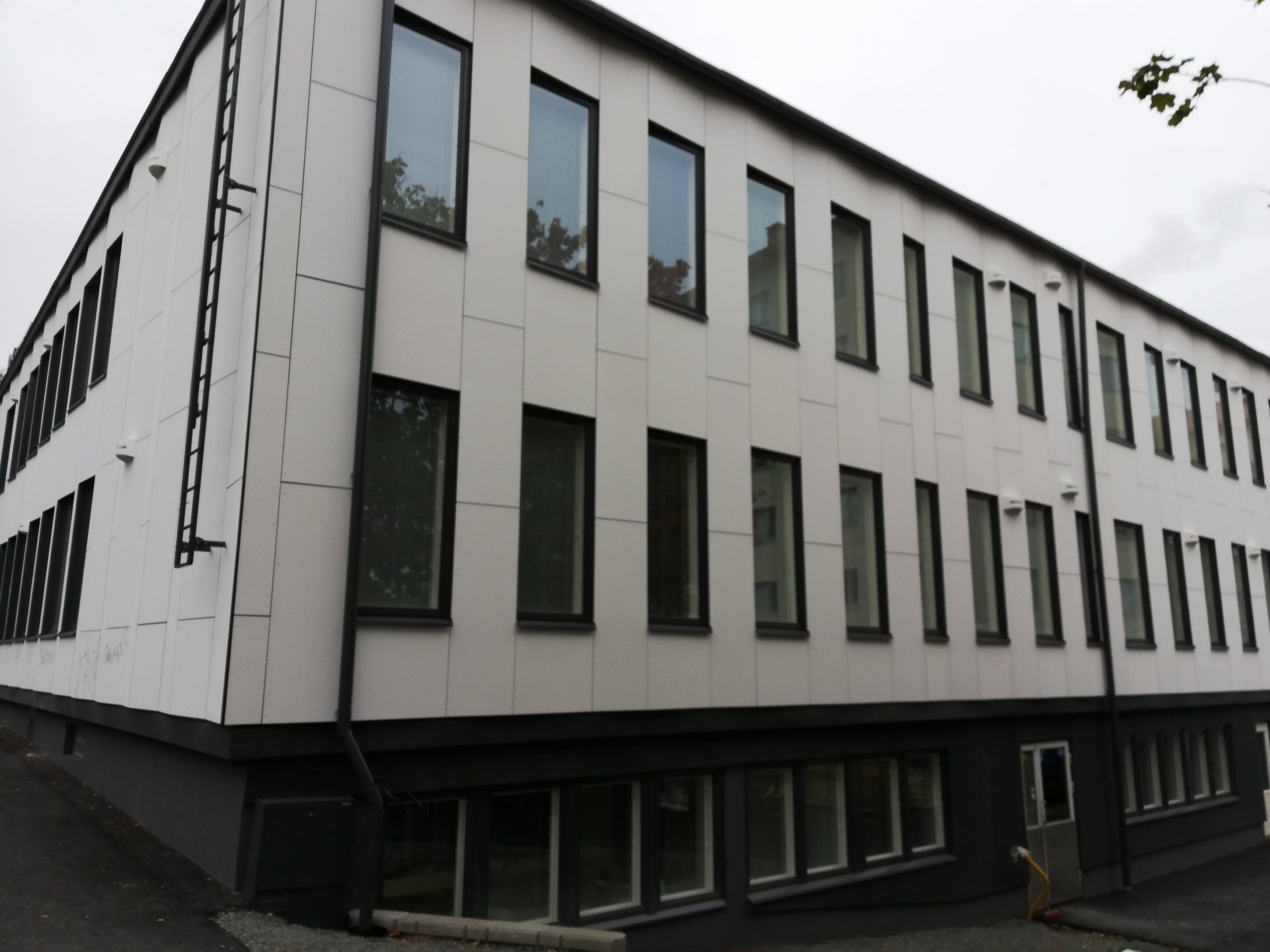 Moderni rakennus, jossa on tasainen julkisivu, useita ikkunoita ja selkeästi erottuva sisäänkäynti.