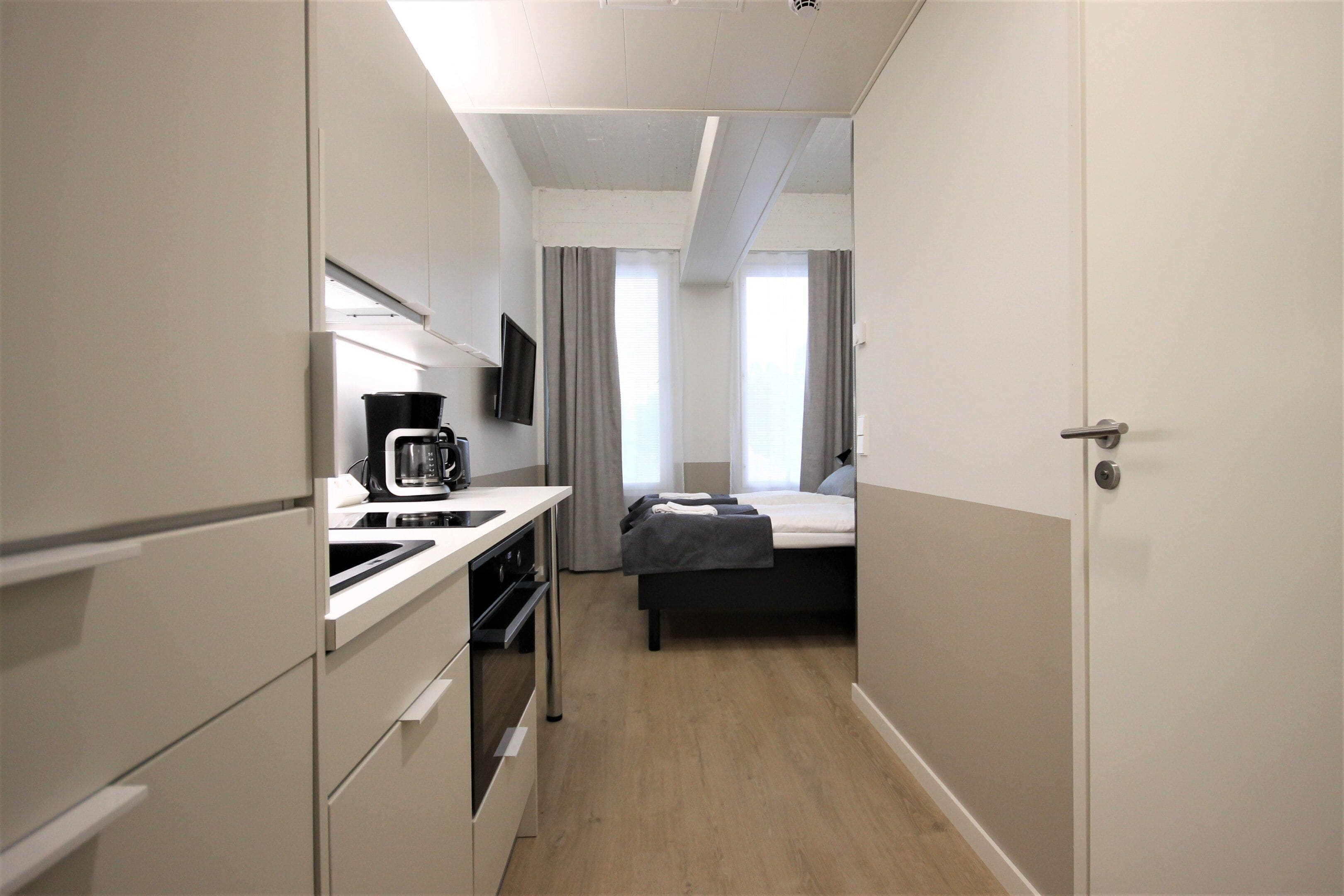 Een kleine hotelkamer met kitchenette, een bed en een badkamer.